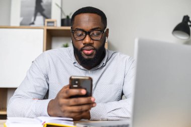 Telefonunu tamir eden Afro-Amerikalı adam.