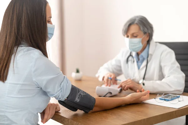 Médica sênior verificando a pressão arterial — Fotografia de Stock