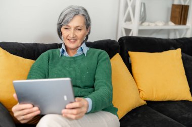 Orta yaşlı bir kadın dokunmatik yastıkta selfie çekiyor.