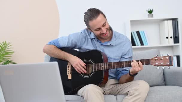 Een hipster leert gitaar spelen. — Stockvideo