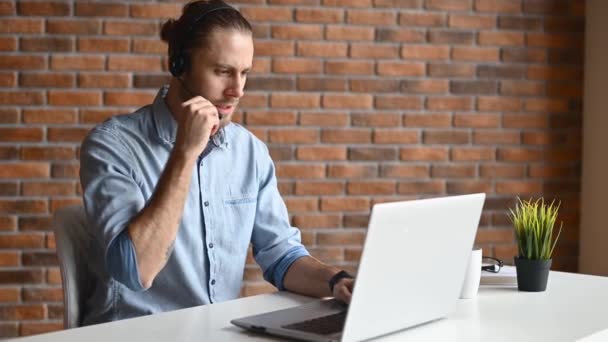 Een man met een laptop en een headset indoor — Stockvideo