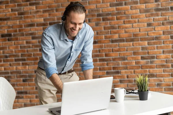 Joven hombre de negocios con auriculares mirando el portátil — Foto de Stock