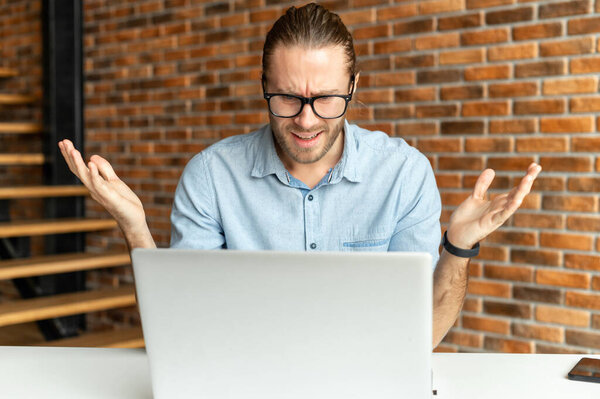 Frustrated young businessman in front of a laptop