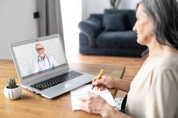 Старша жінка розмовляє з лікарем онлайн — стокове фото