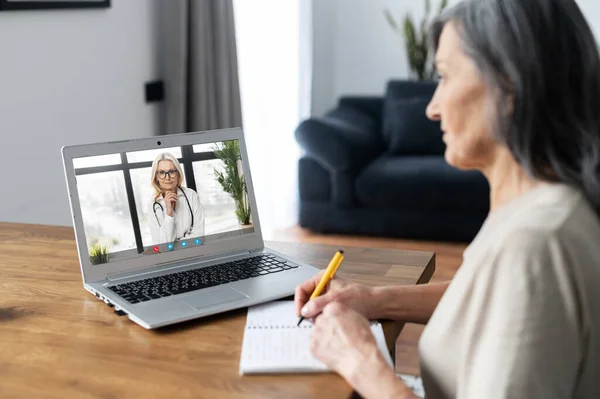 Старша жінка розмовляє з лікарем онлайн — стокове фото