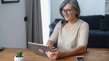 Tablet kullanan orta yaşlı bir kadın.
