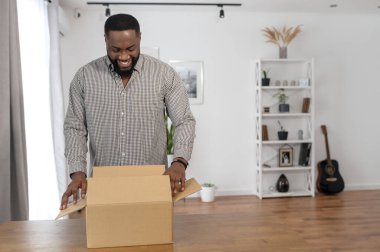 Adamın biri evde bir paket kutusu açıyor.
