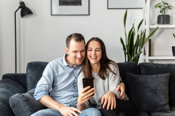 Um casal está usando smartphone em casa — Fotografia de Stock