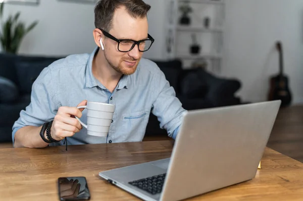 Ένας τύπος χρησιμοποιεί το laptop κάθεται στο γραφείο — Φωτογραφία Αρχείου