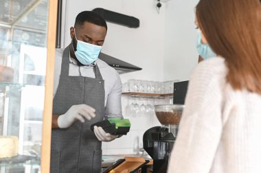 Tıbbi maskeli Afrikalı bir garson.