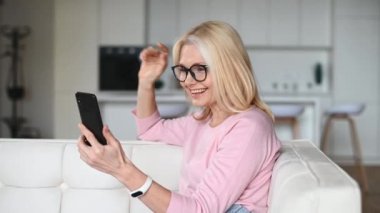 Video görüşmesi için akıllı telefon kullanan orta yaşlı bir kadın.