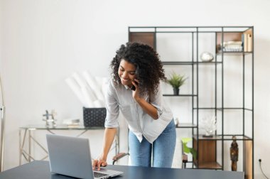 Laptop ve cep telefonu kullanan Afrikalı Amerikalı bir kadın.