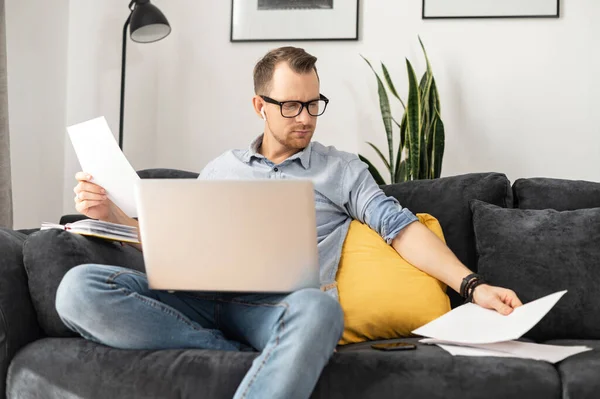 Een freelancer met een laptop die papierwerk doet — Stockfoto