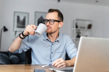 Adamın biri masada otururken dizüstü bilgisayar kullanıyor.