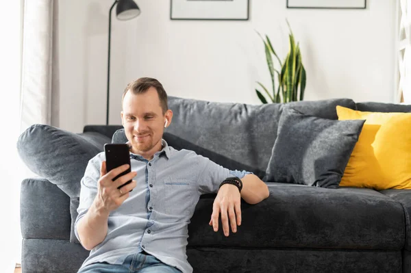 Um cara freelancer está usando smartphone em casa — Fotografia de Stock