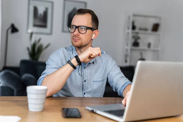 Ένας τύπος χρησιμοποιεί το laptop κάθεται στο γραφείο — Φωτογραφία Αρχείου