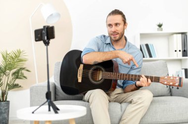 Bir adam içeride gitar çalıyor.