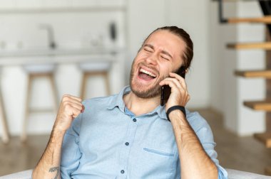 Kanepede oturan bir adam akıllı telefon kullanıyor.