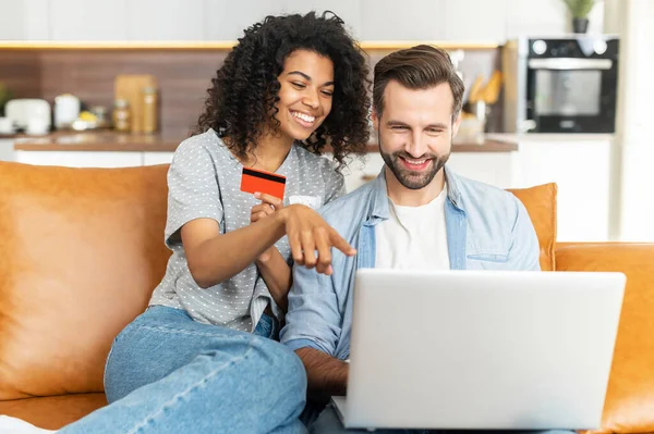 Coppia multirazziale con un computer portatile sul divano — Foto Stock