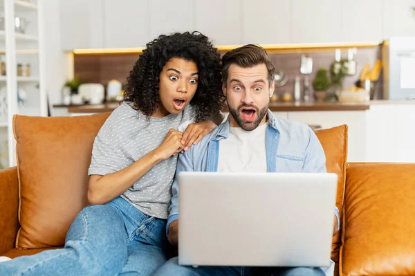 Casal multirracial com um laptop no sofá — Fotografia de Stock