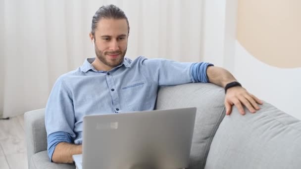 Ein Hipster-Typ benutzt einen Laptop drinnen — Stockvideo