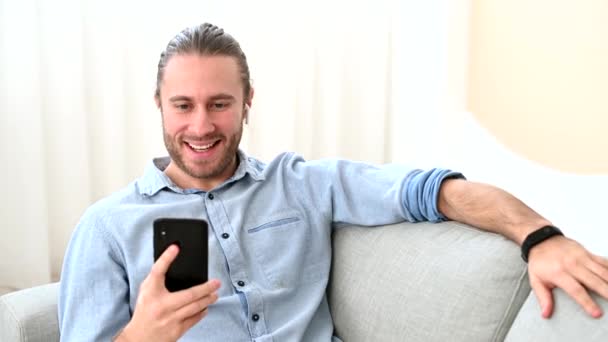 Hippi bir adam kapalı alanda akıllı telefon kullanıyor. — Stok video