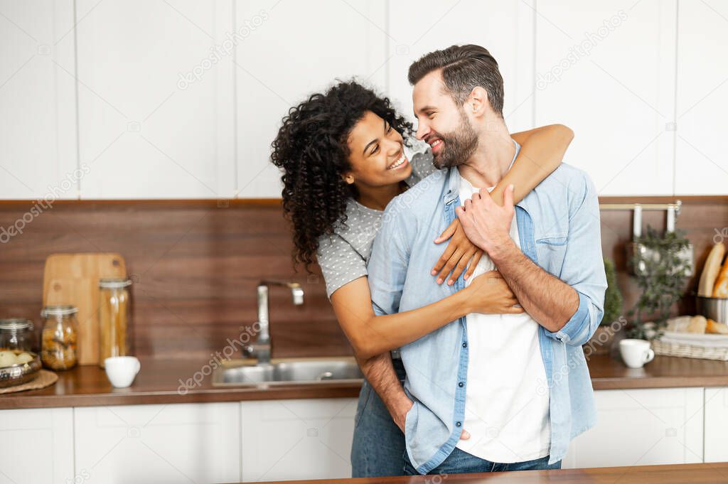 Happy interracial couple standing in the kitchen