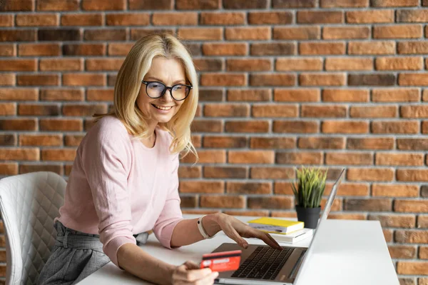 Madura mujer de negocios utilizando ordenador portátil y tarjeta de crédito — Foto de Stock