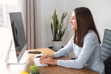 Genç bir kadın ofiste bilgisayar kullanıyor.