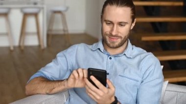 Hippi bir adam kapalı alanda akıllı telefon kullanıyor.