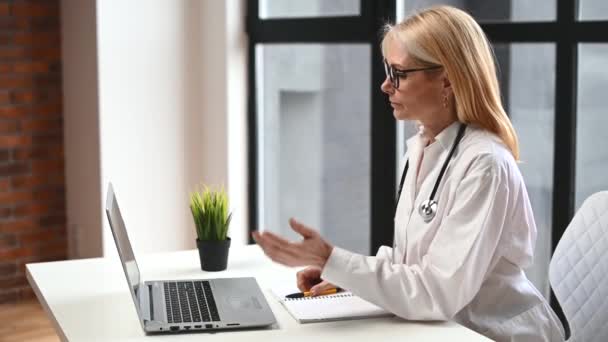 Female doctor gown talking with patient online — Stock Video