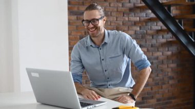 Hipster bir adam içeride dizüstü bilgisayar kullanıyor.