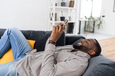 Milenyum Afrikalı Amerikalı adam kanepede yatıyor.