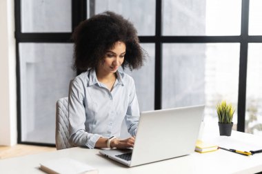 Dizüstü bilgisayarla çalışan odaklanmış melez iş kadını