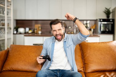 Sıradan gömlek giyen yakışıklı sakallı adam video oyunu oynuyor.