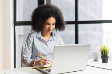 Dersi dikkatle dinleyen ve notlar alan genç bir öğrenci.