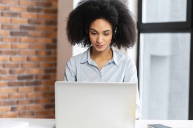 Kulaklıkla odaklanmış melez bir iş kadını.