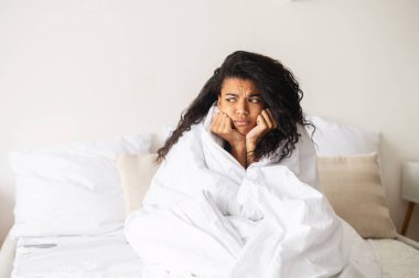 Yumuşak bir battaniyeye sarılmış melez bir kadın.