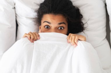 Yatakta yatarken gözleri açık, siyah saçlı, melez bir kadın.