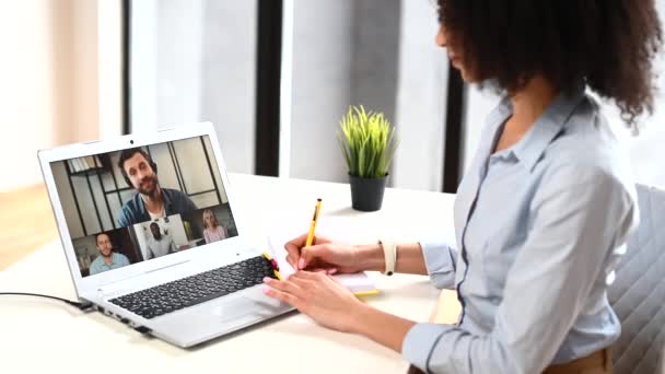 Çift ırklı genç bir kadın içeride video bağlantısı için laptop kullanıyor. — Stok video
