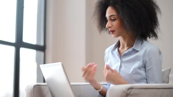 Una giovane donna birazziale sta utilizzando un computer portatile per la connessione video al coperto — Video Stock