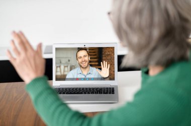 Video araması için dizüstü bilgisayar kullanan olgun yaşlı bir kadın.