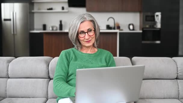 Idősebb idős nő laptopot használ otthon. — Stock videók