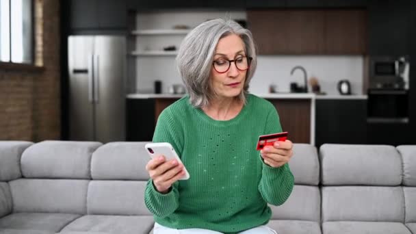 Volwassen senior vrouw is met behulp van een smartphone thuis — Stockvideo