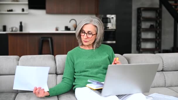 Madura mujer mayor está utilizando un ordenador portátil en casa — Vídeos de Stock