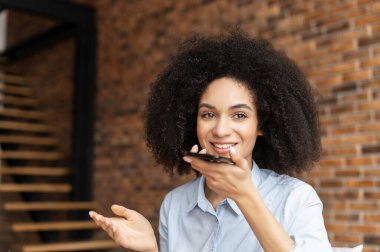 Karışık ırktan bir iş kadını sesli mesaj kaydediyor.