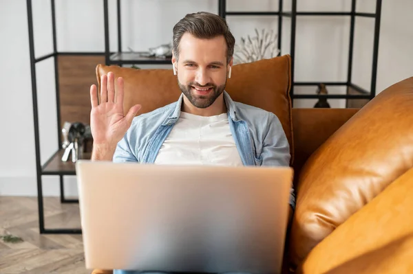 Young bearded hipster guy waving at the laptop — ストック写真