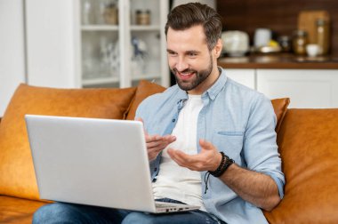 Genç sakallı hippi dizüstü bilgisayarla oturuyor.