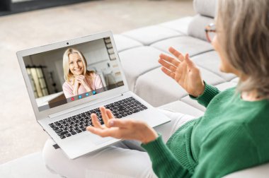 Mutlu orta yaşlı beyaz kadın yetişkin genç kız kadınla video görüşmesi yapıyor.