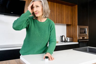 Baş ağrısı olan yaşlı bir kadın.